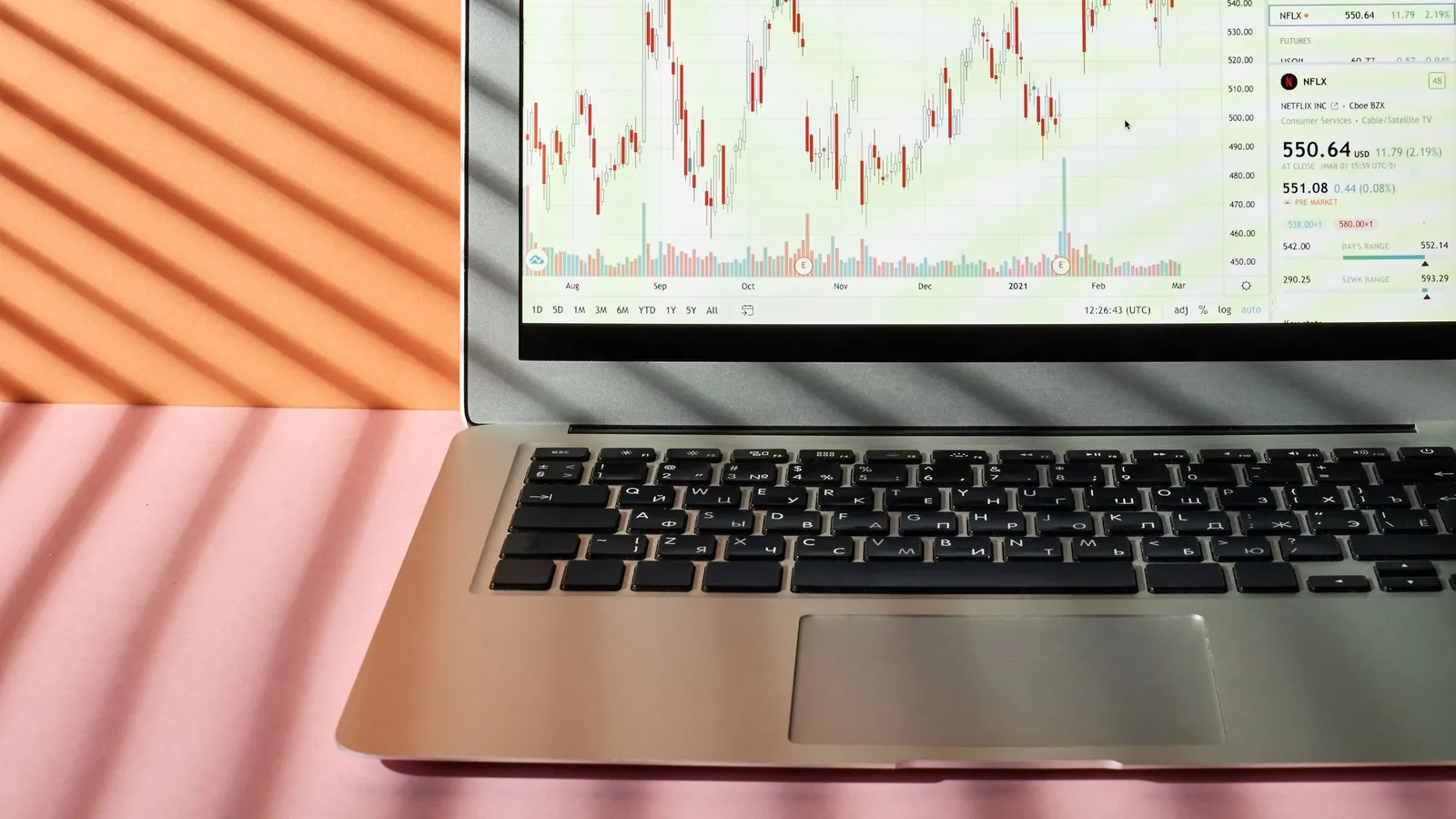 Laptop on a pink desk showing a line chart of sales data